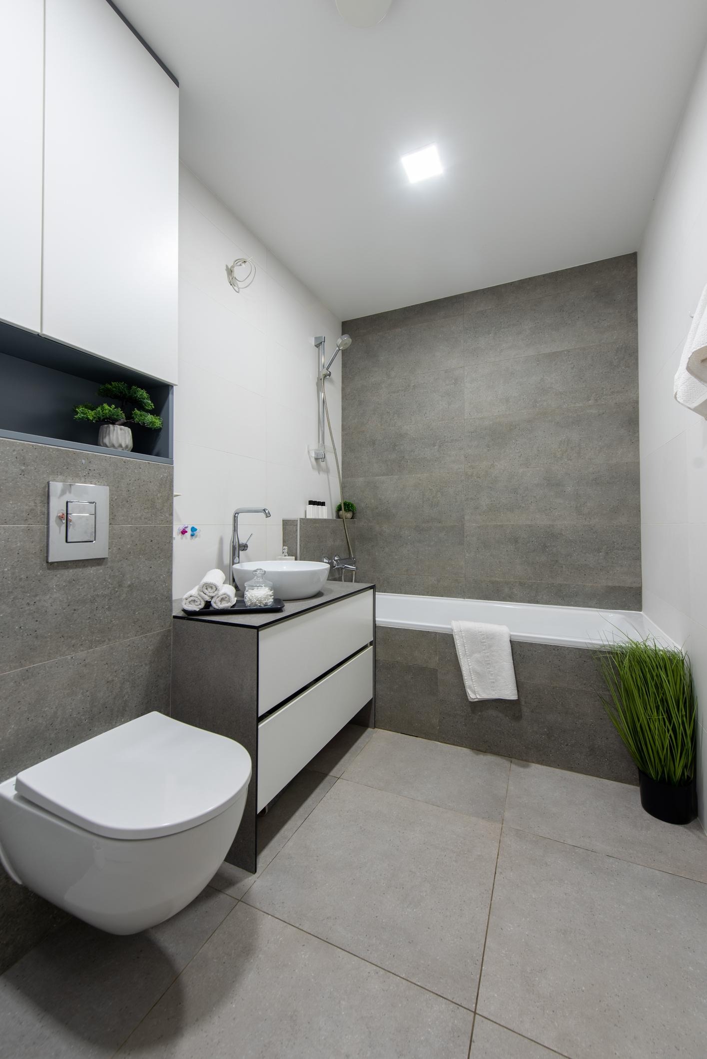 Modernt badrum efter genomförd badrumsrenovering med stora kakelplattor, vägghängd toalett, kommod och badkar. Ett exempel på ett färdigt våtrum där materialval och utförande samverkar i en stilren och funktionell lösning.